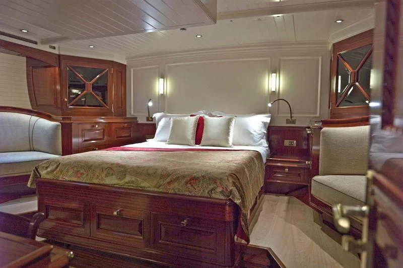 a bed with a couple of chairs and a dresser in a room aboard RAINBOW Yacht for Sale