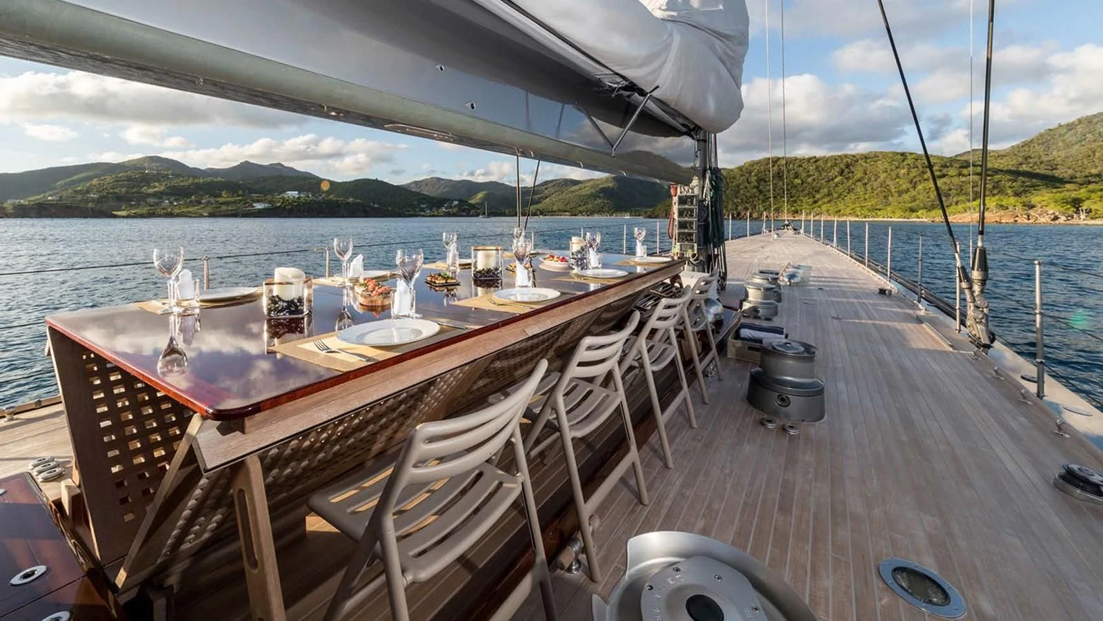 a deck with a table and chairs on it by a body of water aboard RAINBOW Yacht for Sale
