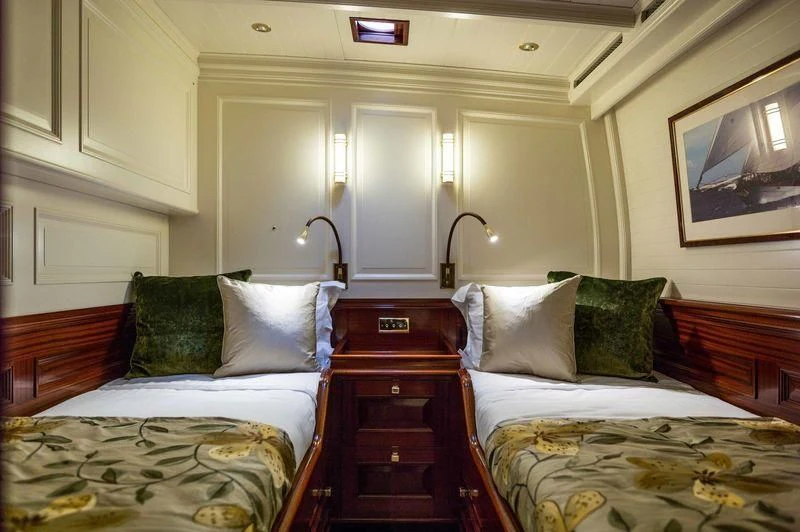 a room with beds and a dresser aboard RAINBOW Yacht for Sale
