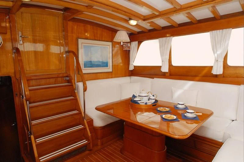 a wooden cabin with a table and chairs aboard GITANA IV Yacht for Sale