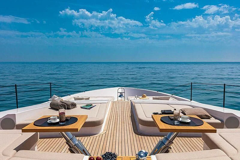 a deck with a table and chairs on it by the ocean aboard RINO Yacht for Sale