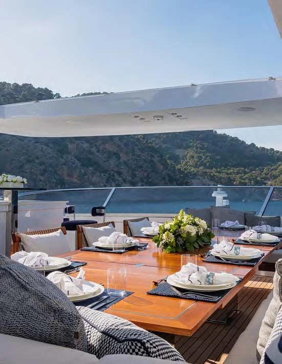 a table with plates and a view of a body of water aboard NEW WAVES Yacht for Sale