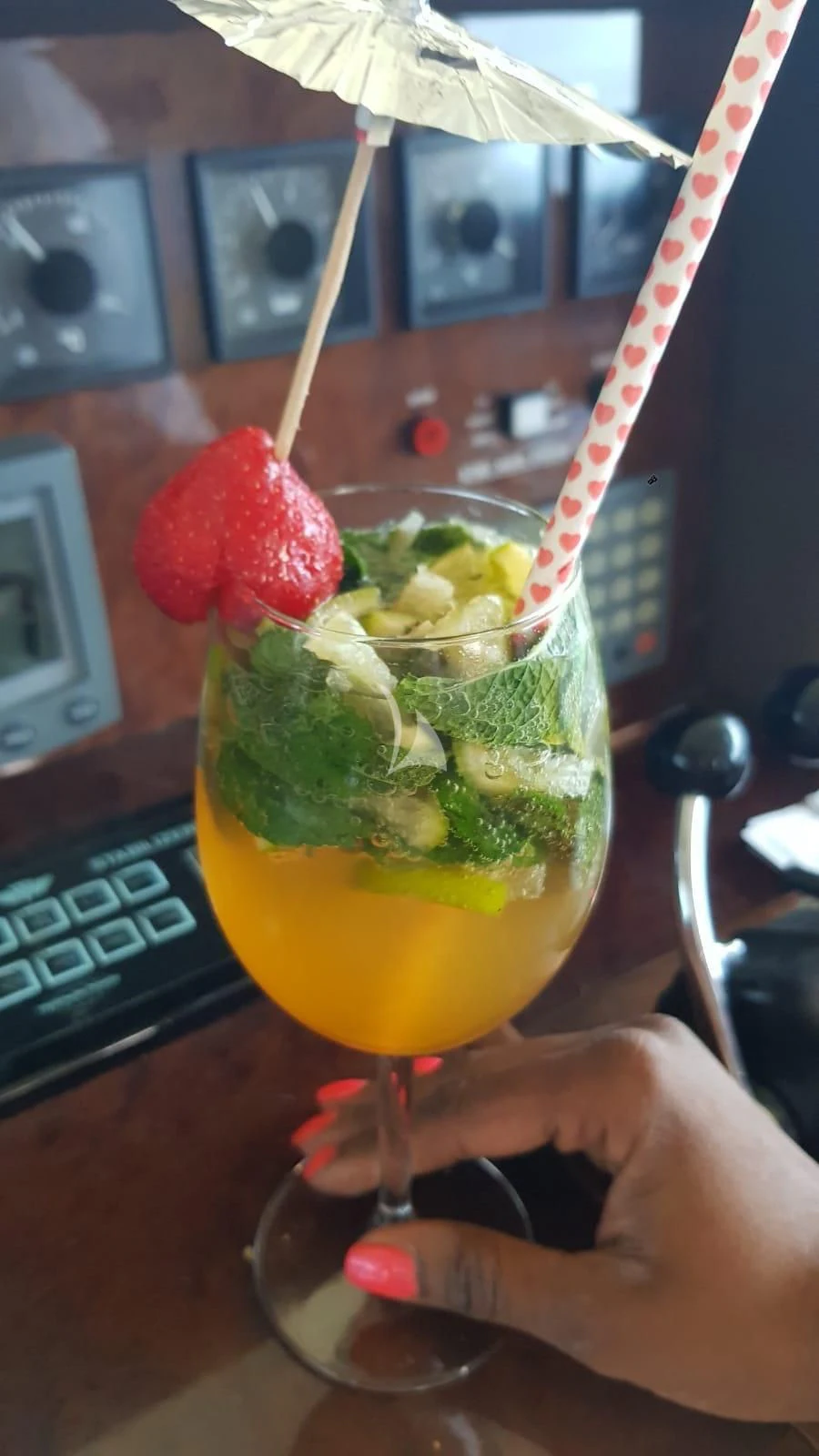 a hand holding a drink with straws and fruit in it aboard MISS CANDY Yacht for Charter