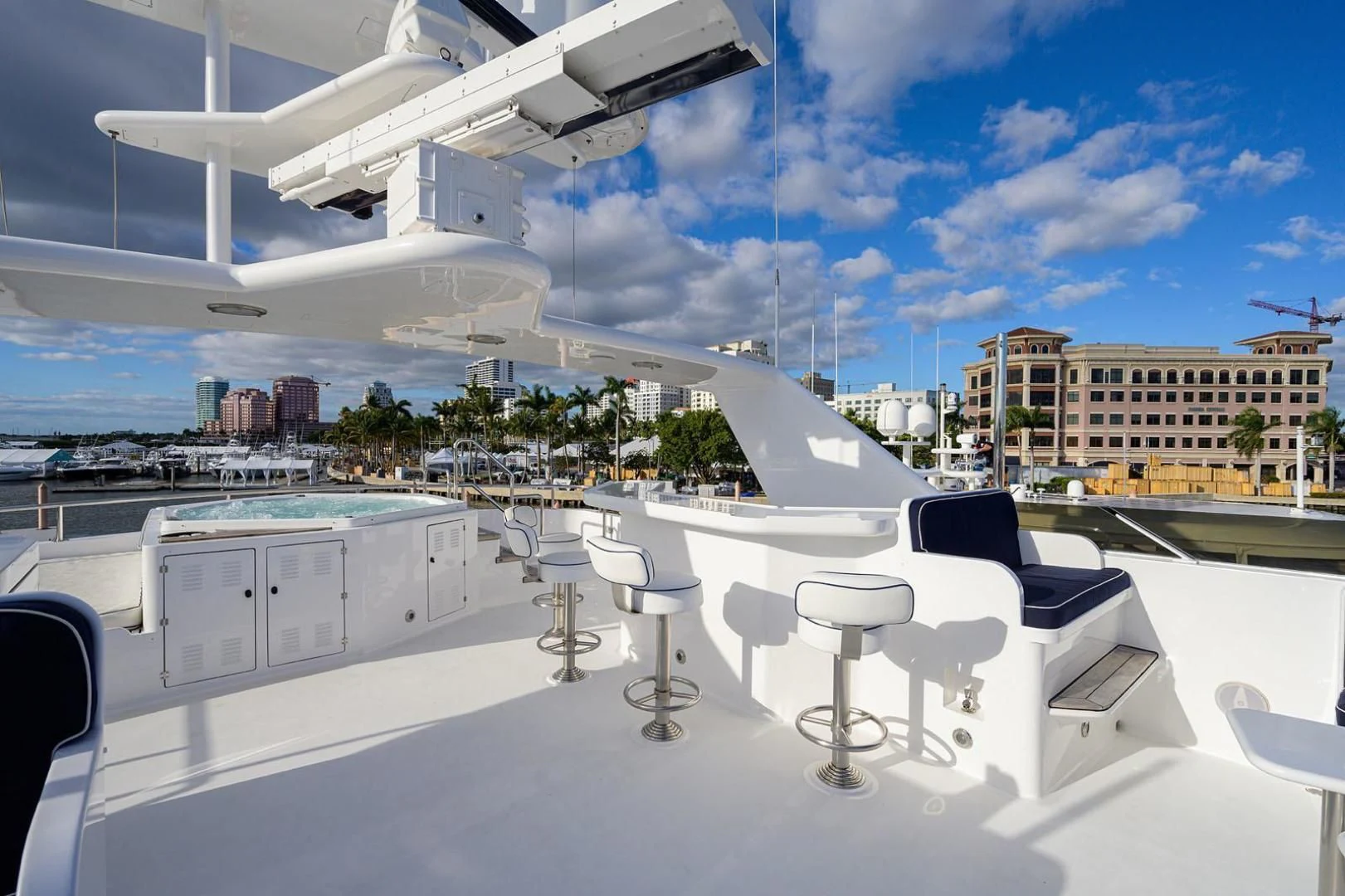 a white lounge chair in front of a large building with a city in the background aboard LEGACY Yacht for Sale