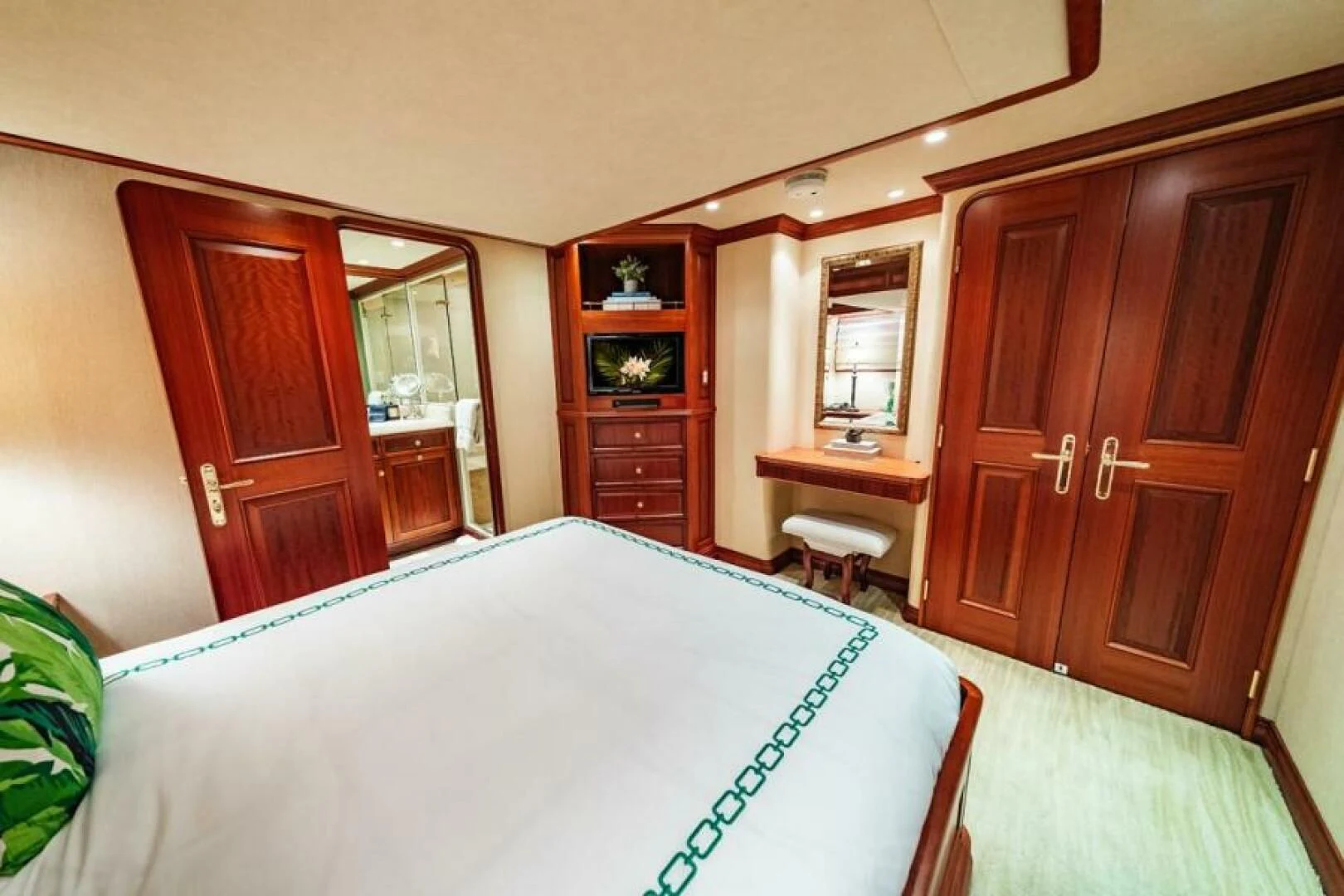 a large bedroom with a large white bed and wooden cabinets aboard LEGACY Yacht for Sale