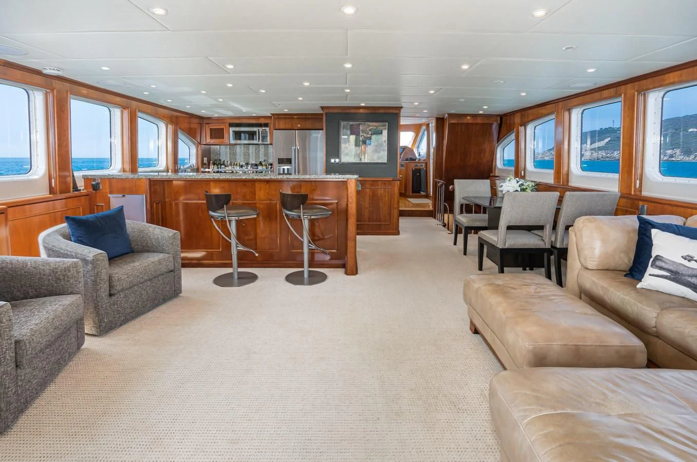 a large living room with a bar and a table aboard LONE WOLF Yacht for Sale