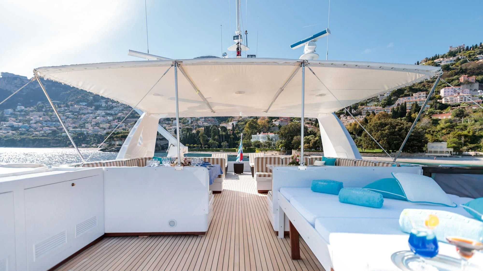 a large white tent with a pool and a deck with a view of a town and water aboard HEMILEA Yacht for Charter