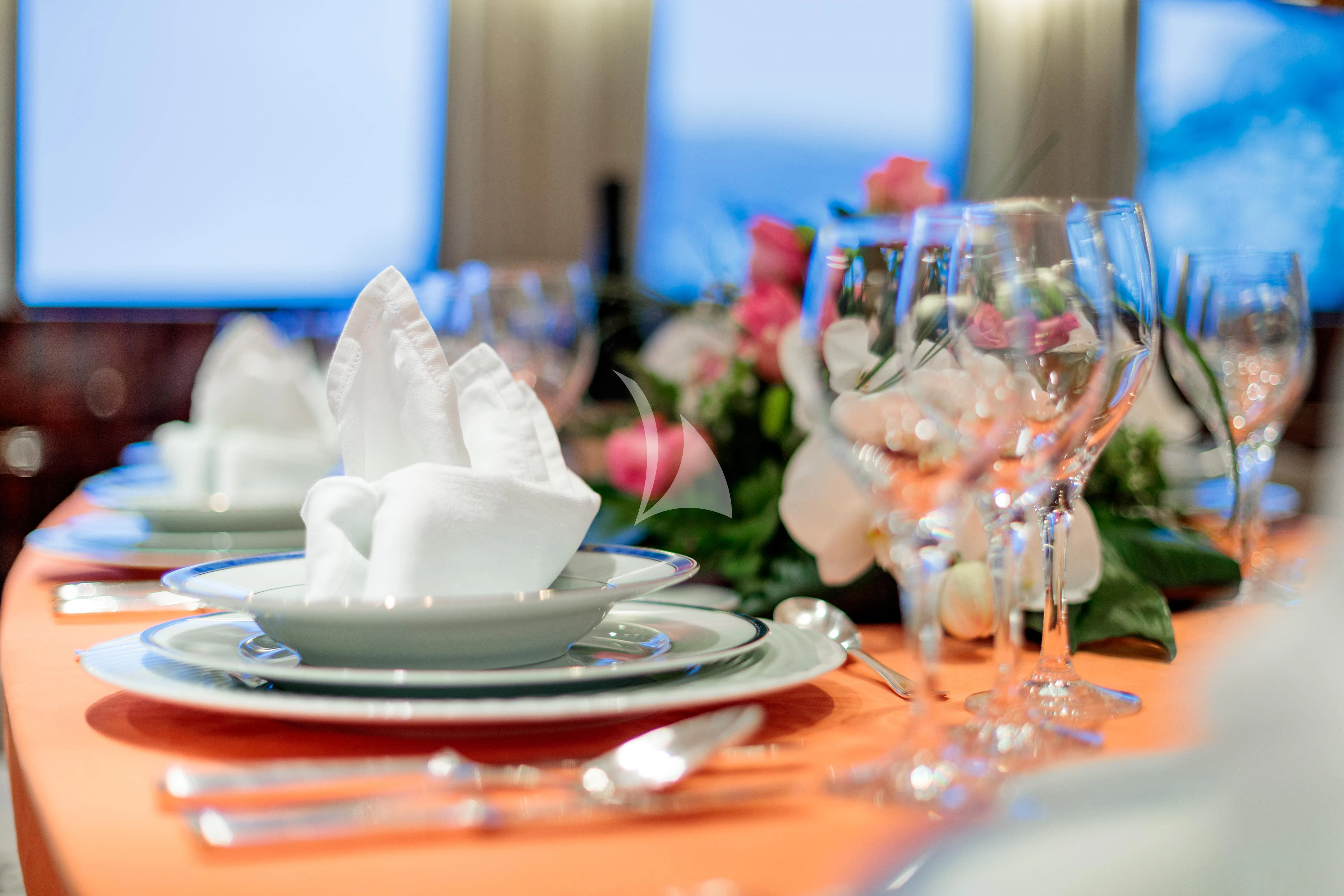 a table with a plate of food and glasses on it aboard HEMILEA Yacht for Charter