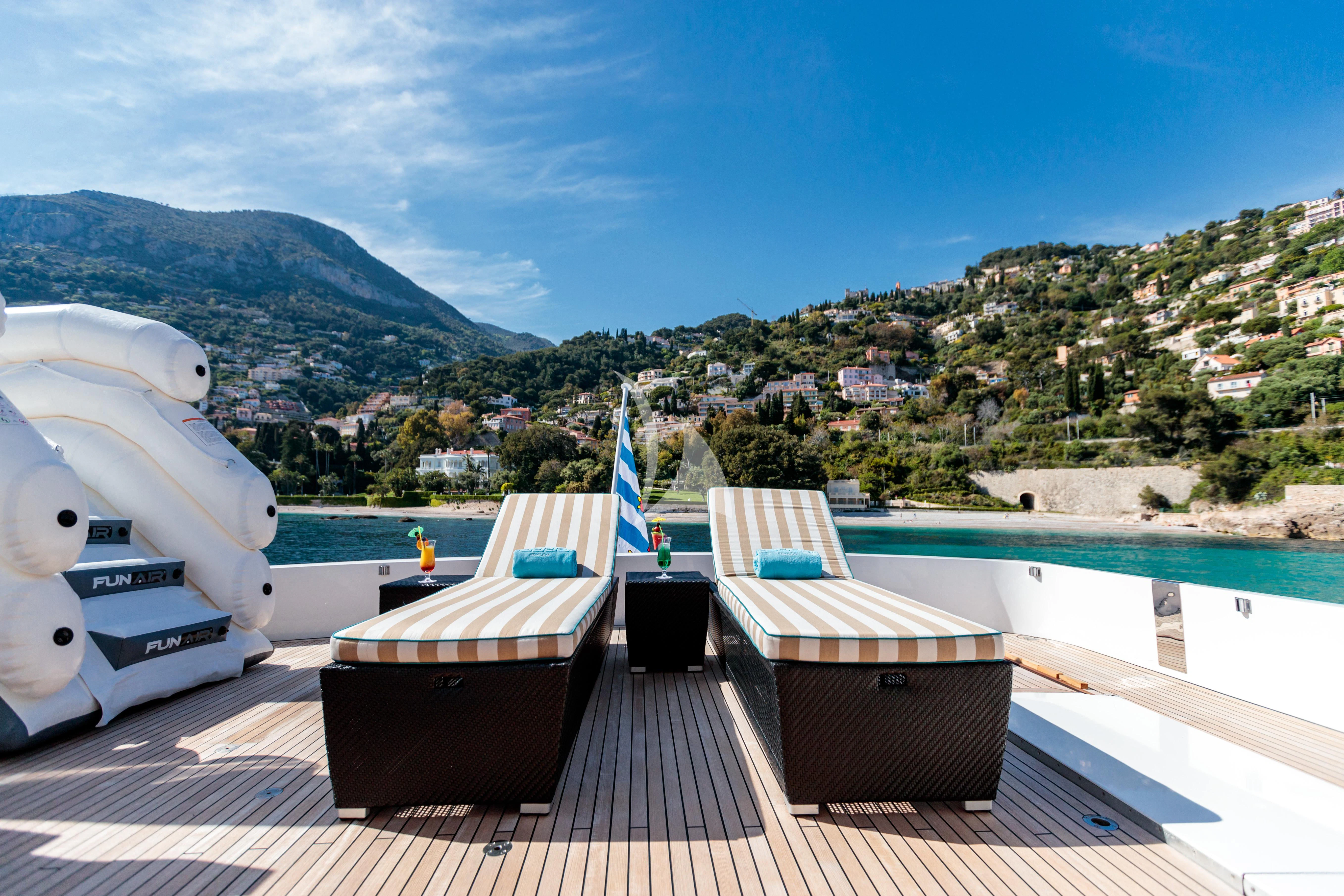 a deck with chairs on it by a body of water with hills in the background aboard HEMILEA Yacht for Charter
