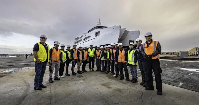 a group of people in hardhats standing in front of a helicopter aboard CHARLEY 2 Yacht for Sale