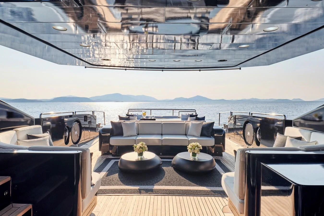 a room with a large couch and a table with chairs and a large body of water in the aboard ABILITY Yacht for Sale