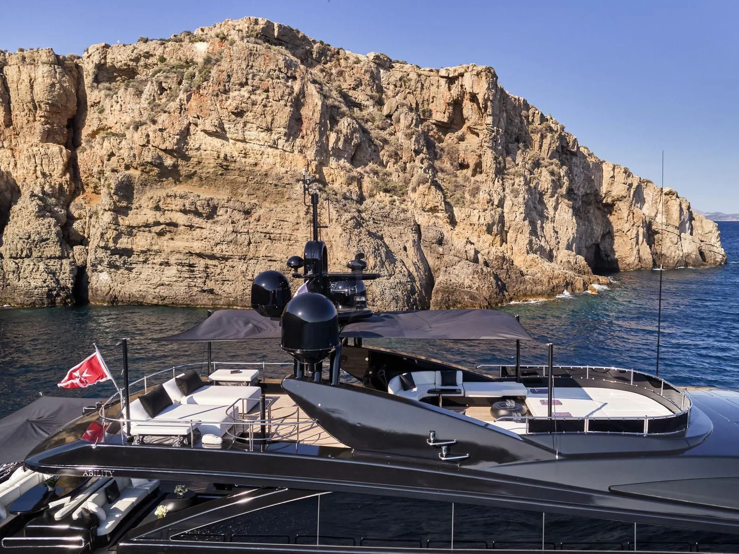 a boat docked in front of a cliff aboard ABILITY Yacht for Sale
