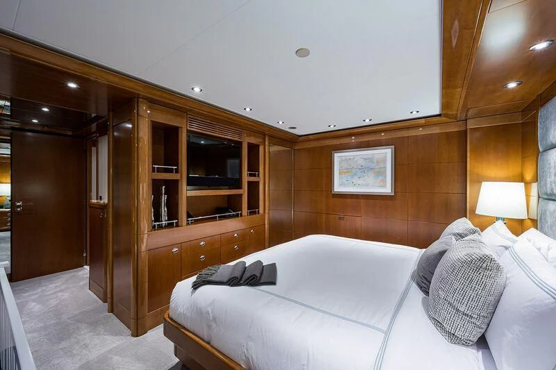 a bedroom with a bed and a wood cabinet aboard SEANASH Yacht for Sale