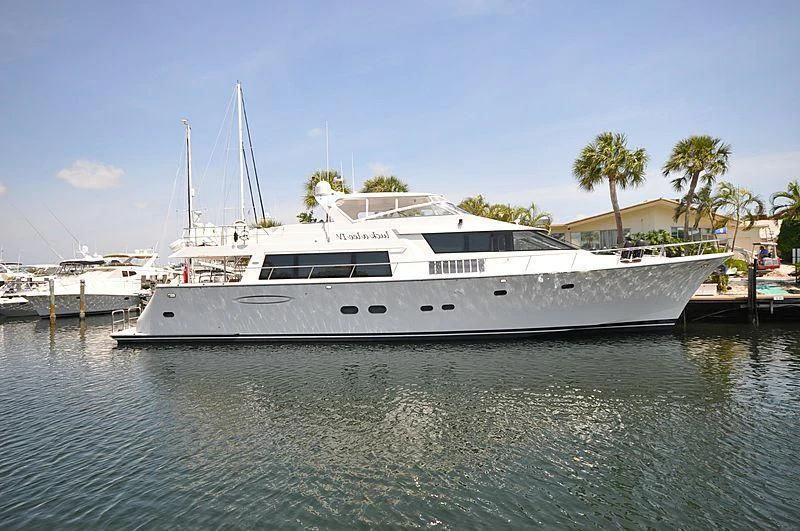 a white boat in a harbor aboard BOOGIE BABE IV Yacht for Sale