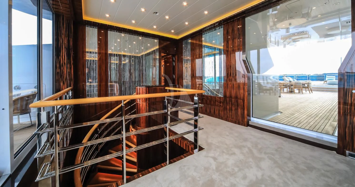 a room with a glass wall and a balcony with a view of the city aboard AHS Yacht for Sale
