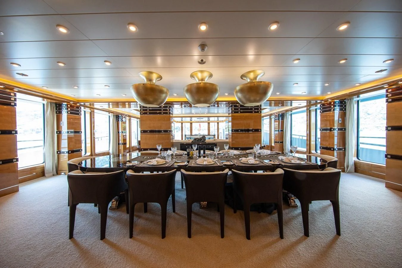 a large dining table in a large room with large windows aboard AHS Yacht for Sale