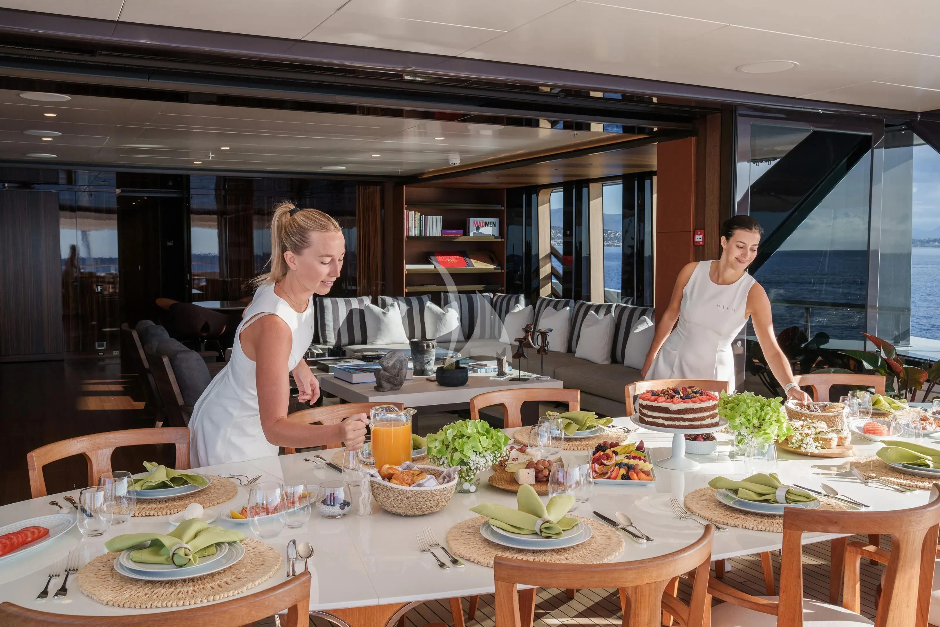 a couple of women stand near a table with food aboard HALO Yacht for Charter