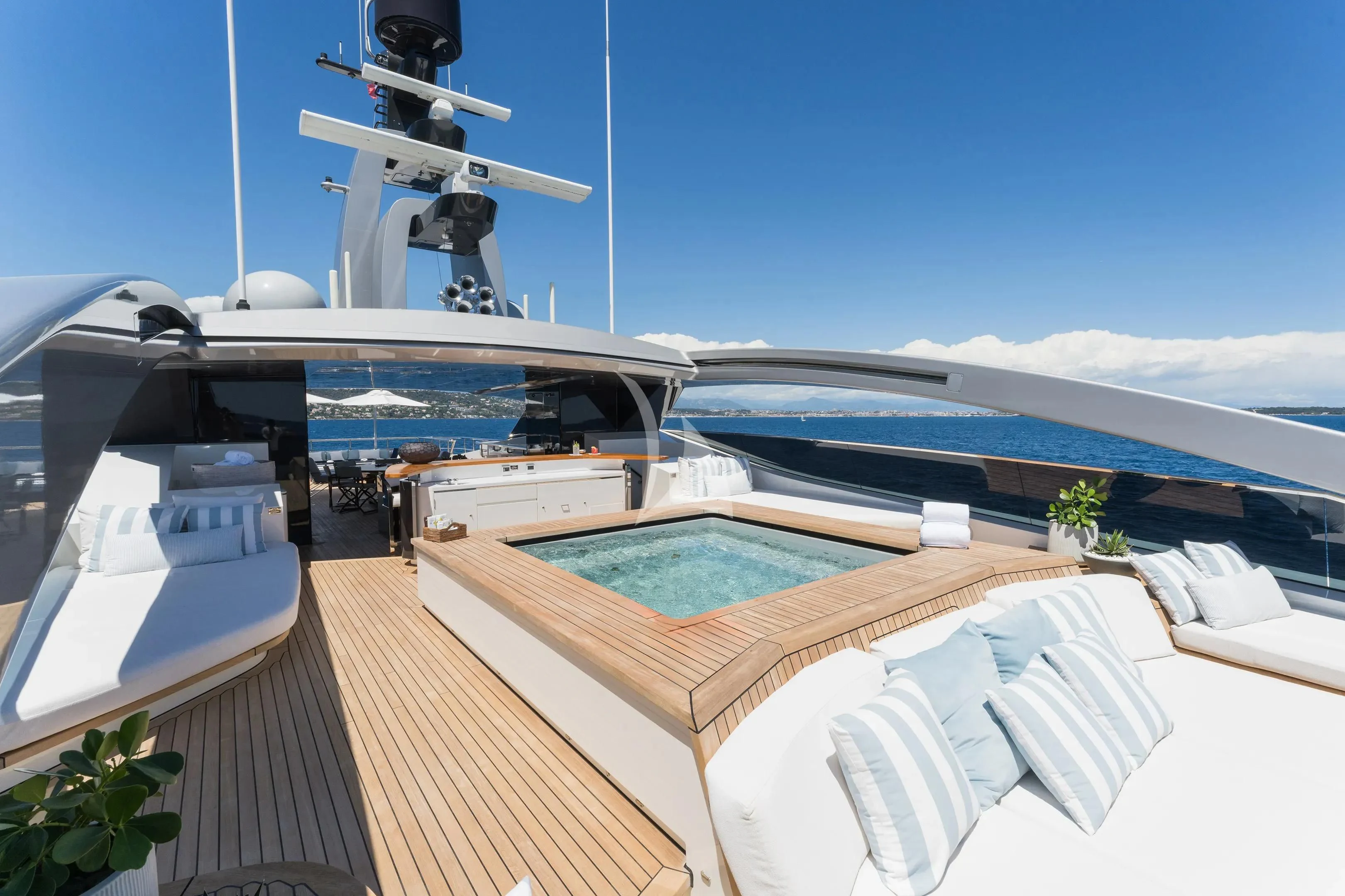 a deck with a pool and a large ship in the background aboard HALO Yacht for Charter