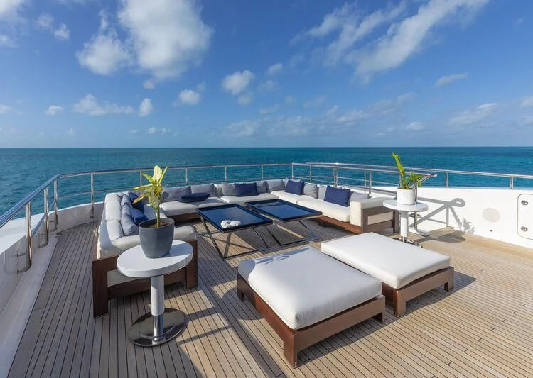 a room with a pool and a deck with chairs and a table aboard HALO Yacht for Charter