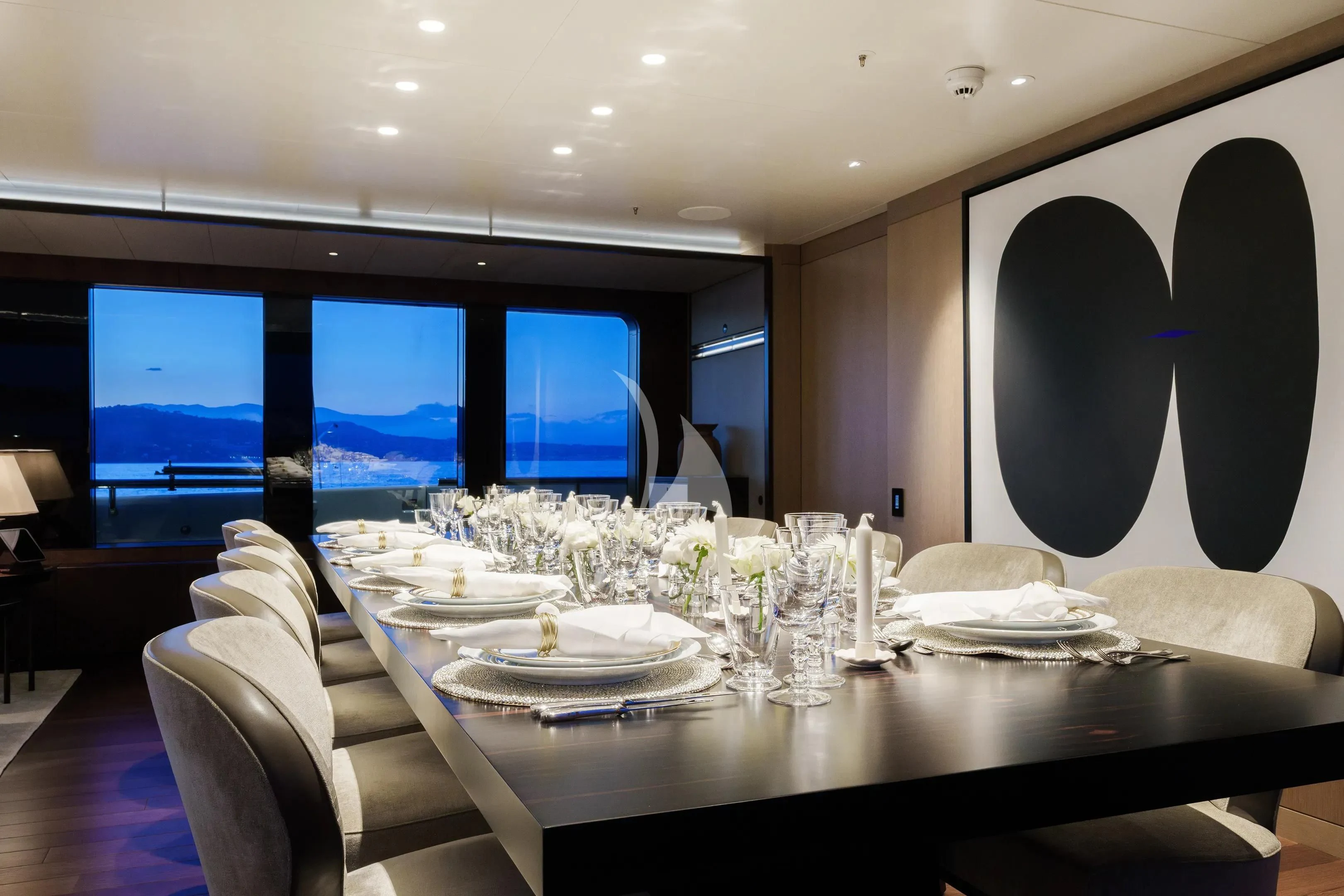 a large room with a table and chairs and a large screen aboard HALO Yacht for Charter