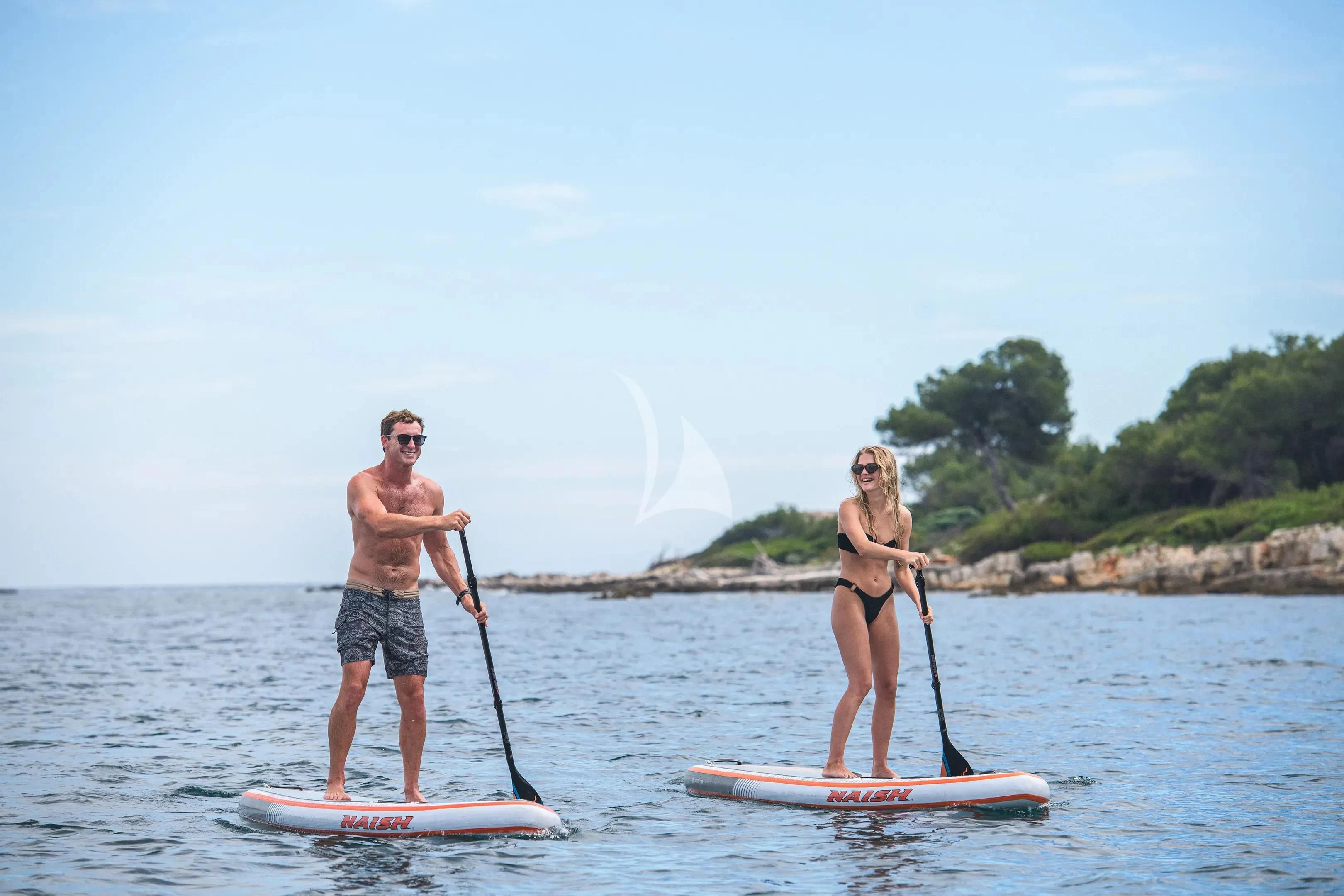 a man and woman on paddle boards aboard HALO Yacht for Charter