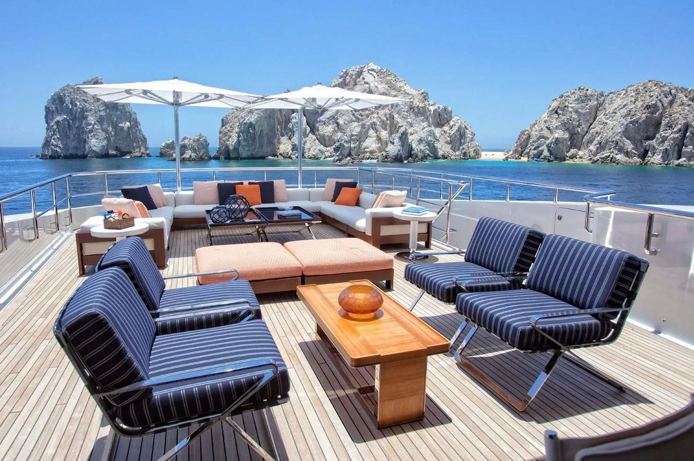 a deck with chairs and tables on it by a body of water aboard HALO Yacht for Charter