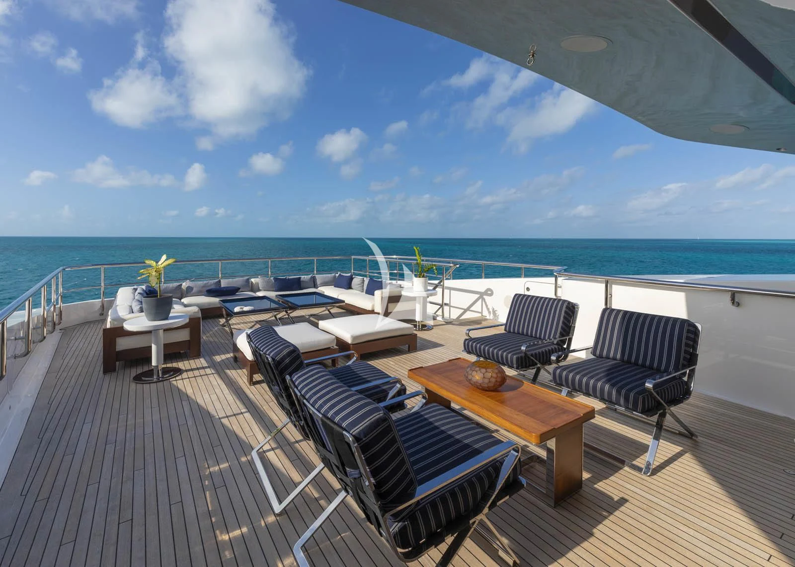 a deck with chairs and tables on it next to a body of water aboard HALO Yacht for Charter