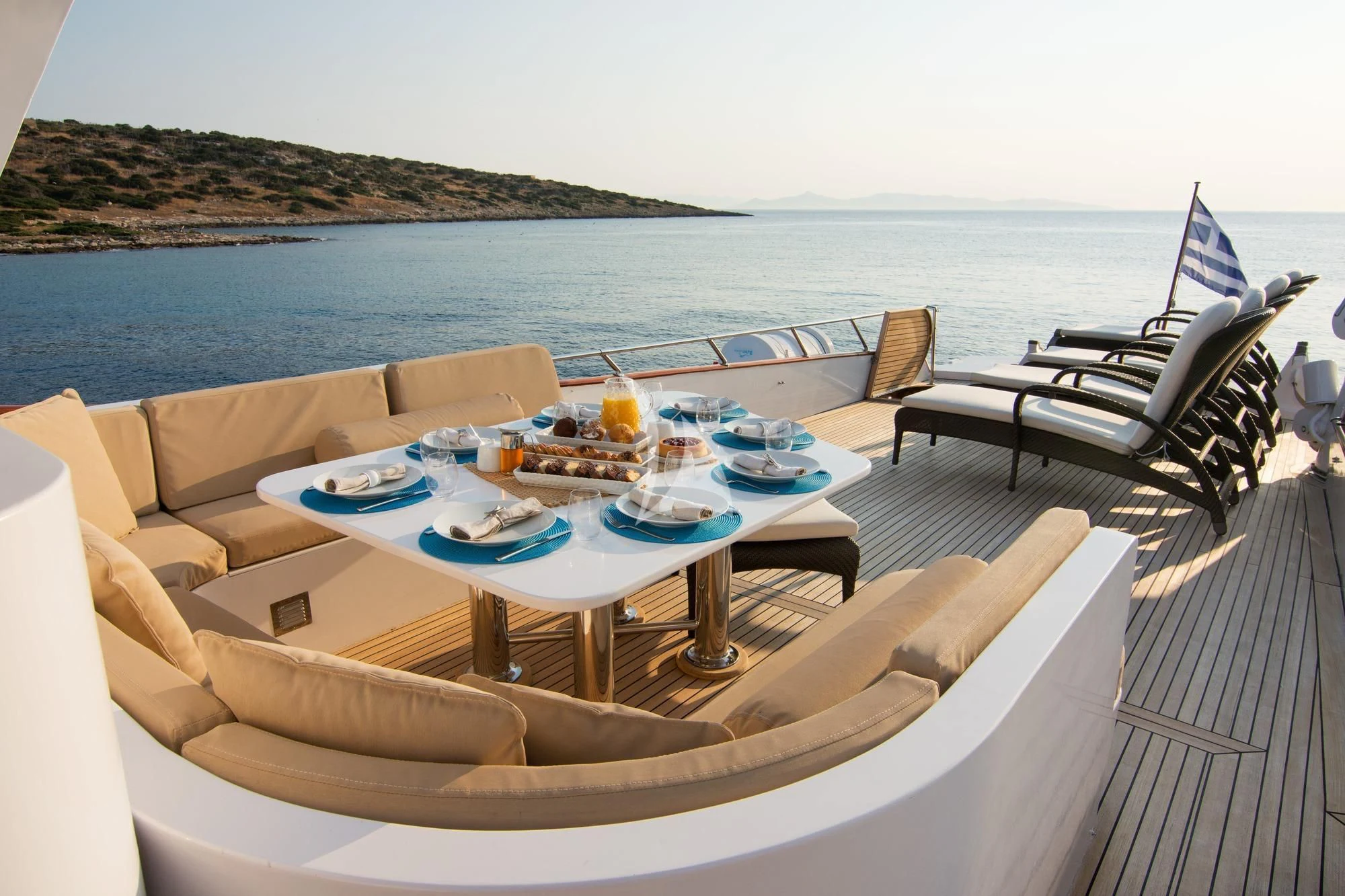 a table with a plate and chairs on a deck overlooking a body of water aboard OCEANE II Yacht for Sale