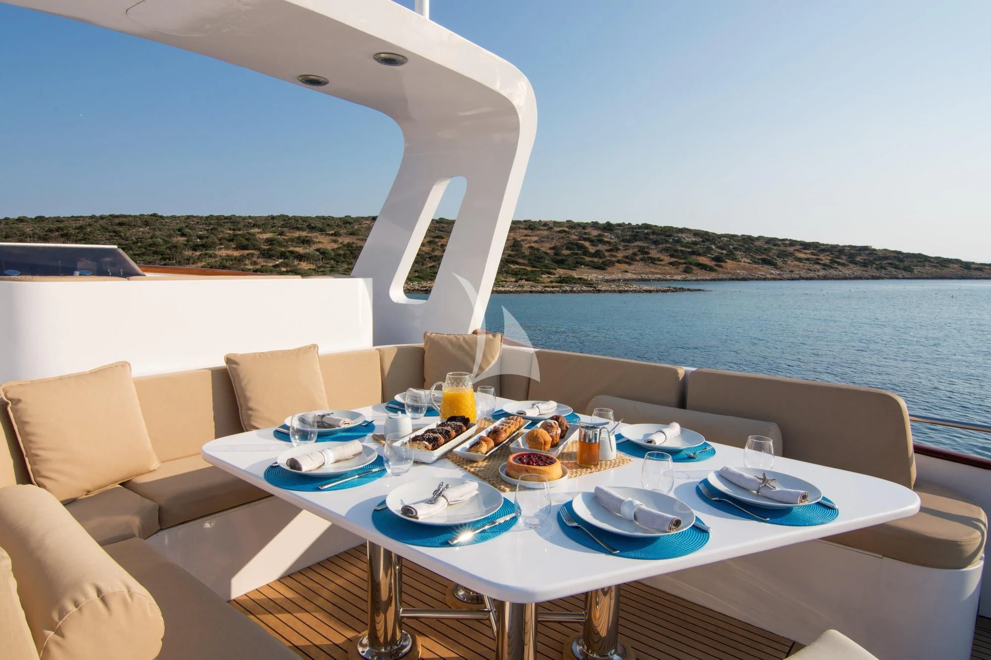 a table with plates and food on it by a large body of water aboard OCEANE II Yacht for Sale