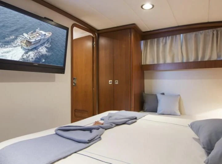 a bed with a white sheet and a wooden door aboard OCEANE II Yacht for Sale