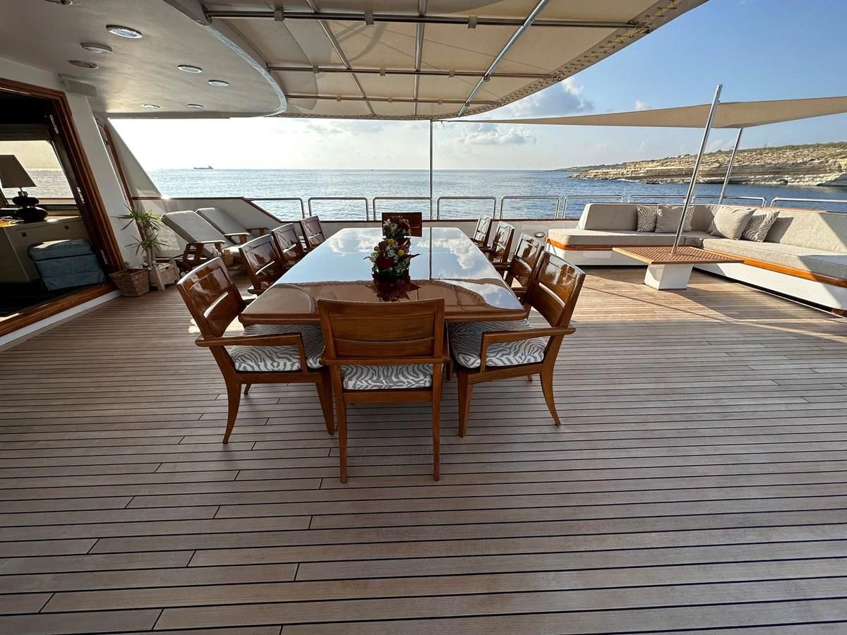 a wooden table and chairs on a deck overlooking a body of water aboard CHEETAH MOON Yacht for Sale