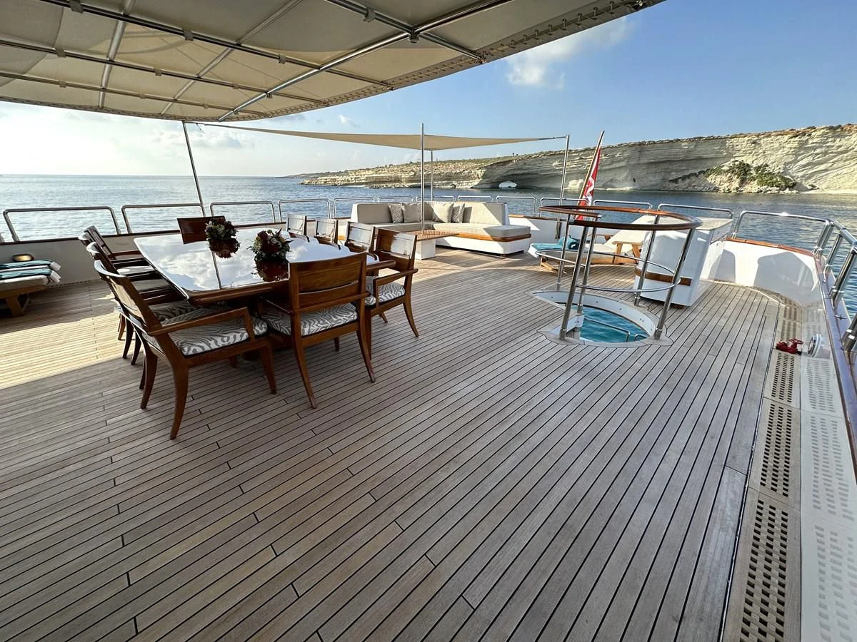 a deck with a table and chairs on it aboard CHEETAH MOON Yacht for Sale