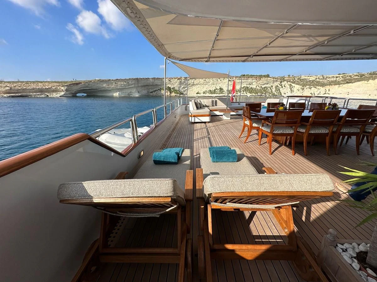 a deck with chairs and tables on it by the water aboard CHEETAH MOON Yacht for Sale