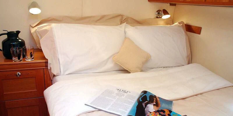 a bed with a white sheet and pillows aboard DARK STAR OF LONDON Yacht for Charter