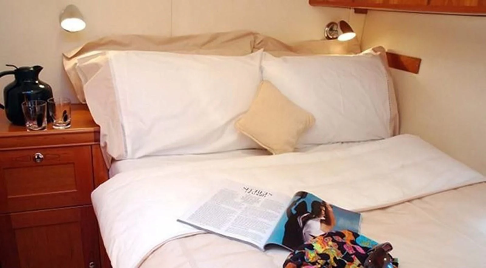 a bed with a book and a pillow on it aboard DARK STAR OF LONDON Yacht for Charter