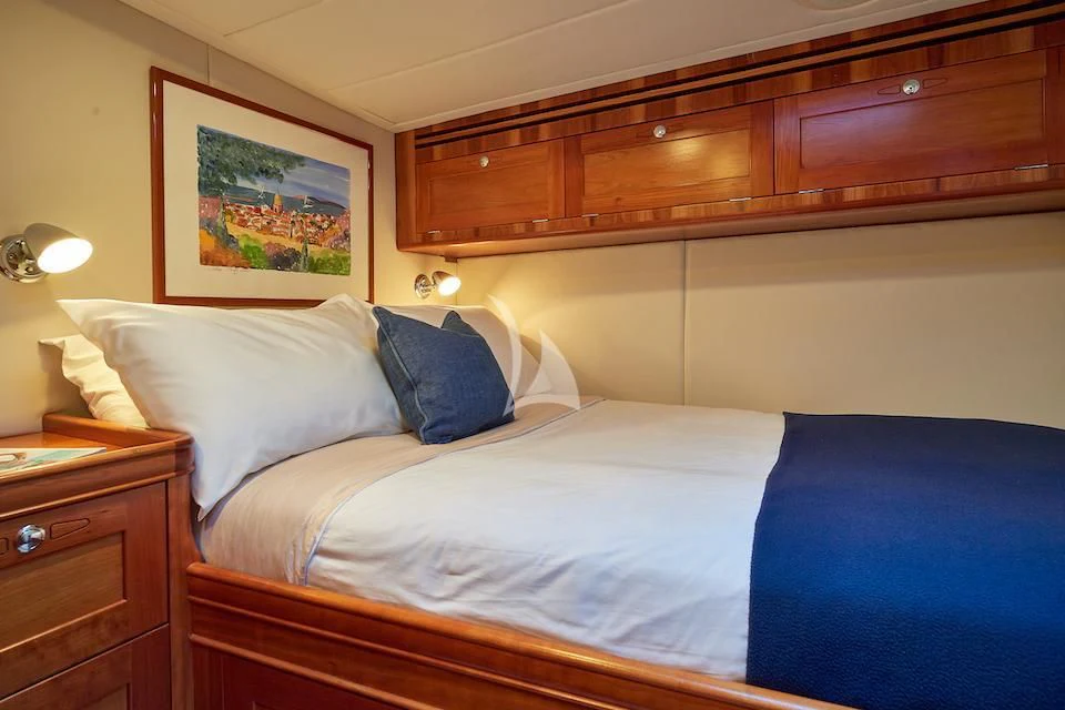 a bed with blue sheets aboard DARK STAR OF LONDON Yacht for Charter