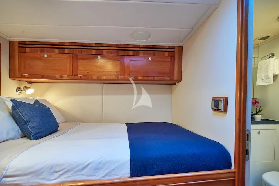 a bed with blue sheets aboard DARK STAR OF LONDON Yacht for Charter