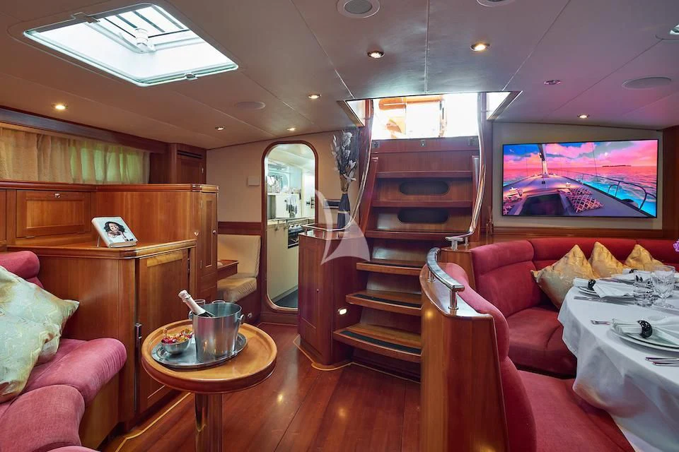 a living room with red couches and a wood table aboard DARK STAR OF LONDON Yacht for Charter