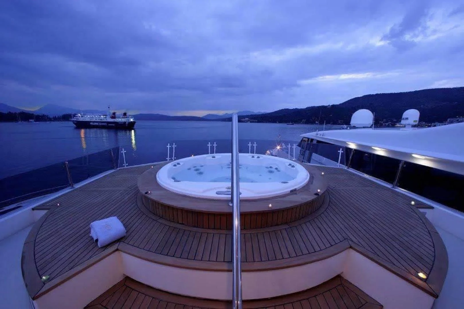 a deck with a pool and a view of the water and mountains in the background aboard CORVUS Yacht for Sale