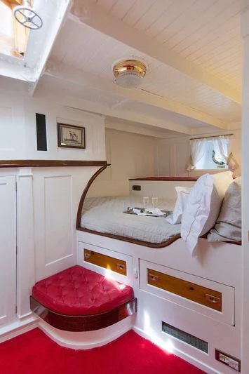 a bedroom with a red rug aboard PURITAN Yacht for Sale