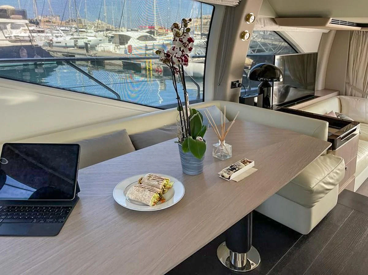 a laptop on a table next to a plate of food aboard OOSA Yacht for Sale