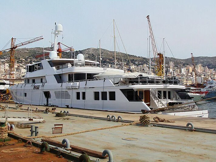 a boat docked at a pier with HMS M33 in the background aboard GRACE Yacht for Sale