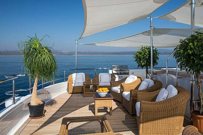 a patio with chairs and a table on a deck with a body of water in the background aboard GRACE Yacht for Sale