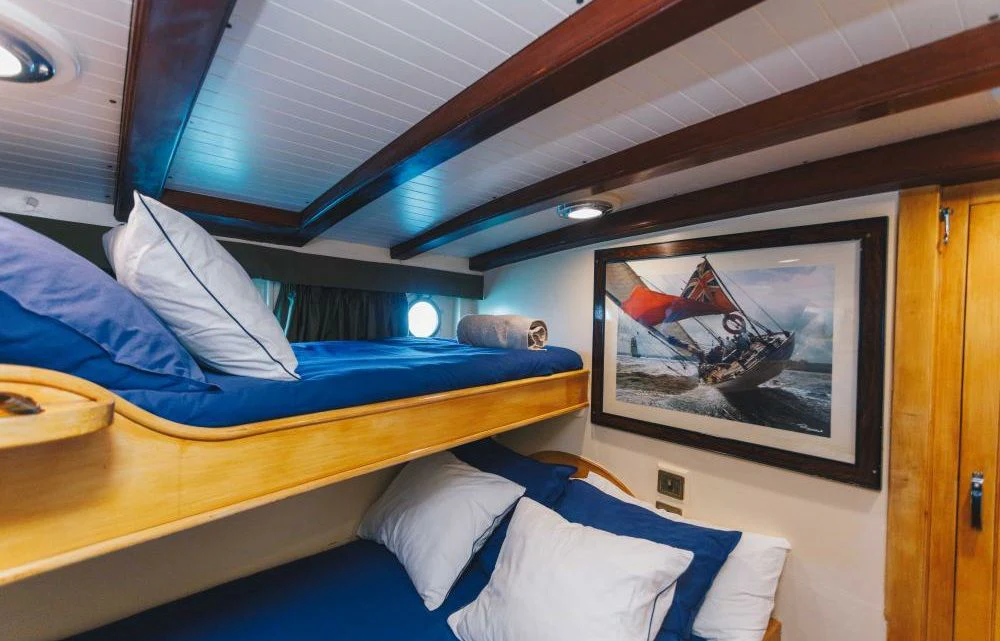 a bed with a blue sheet and a picture on the wall aboard SILVER CAVALIER Yacht for Sale