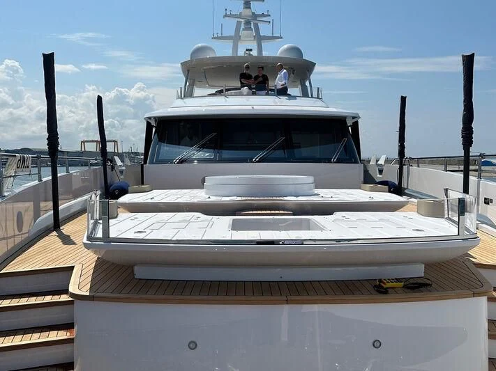 a white boat with a large ship in the background aboard R.DARENBEN Yacht for Sale