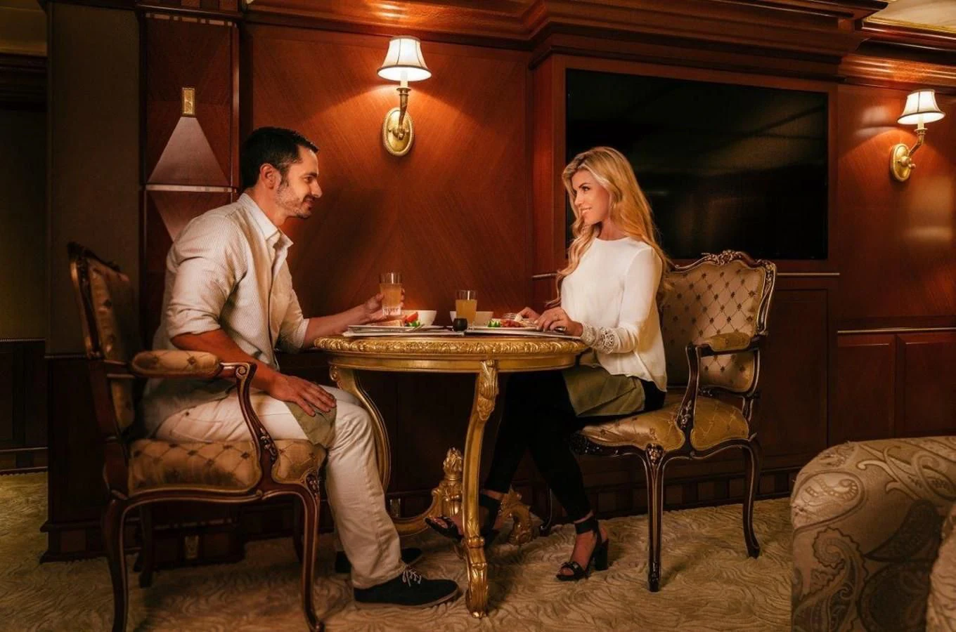 a man and woman sitting at a table with drinks aboard STARSHIP Yacht for Charter