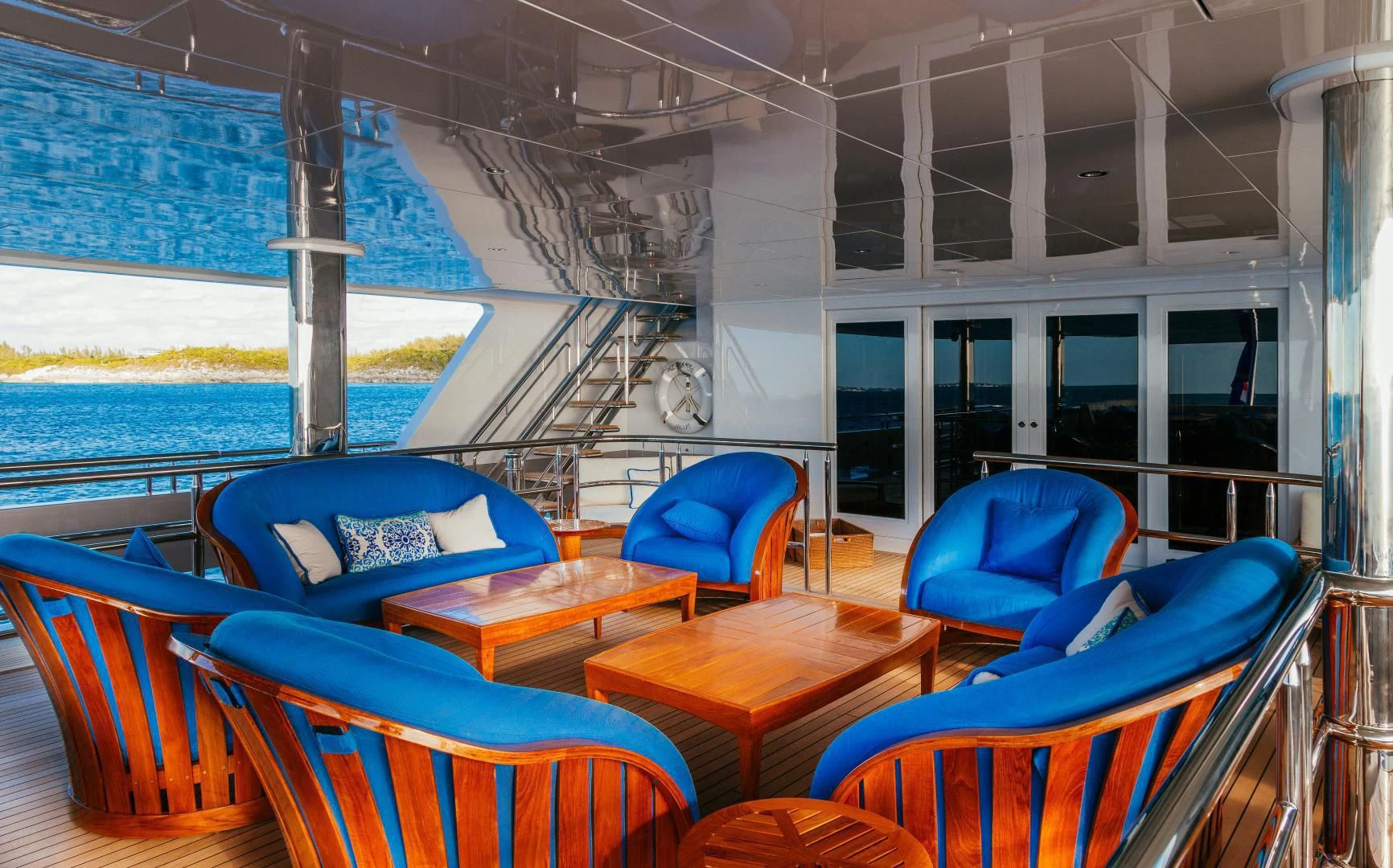 a room with blue chairs and a railing aboard STARSHIP Yacht for Charter