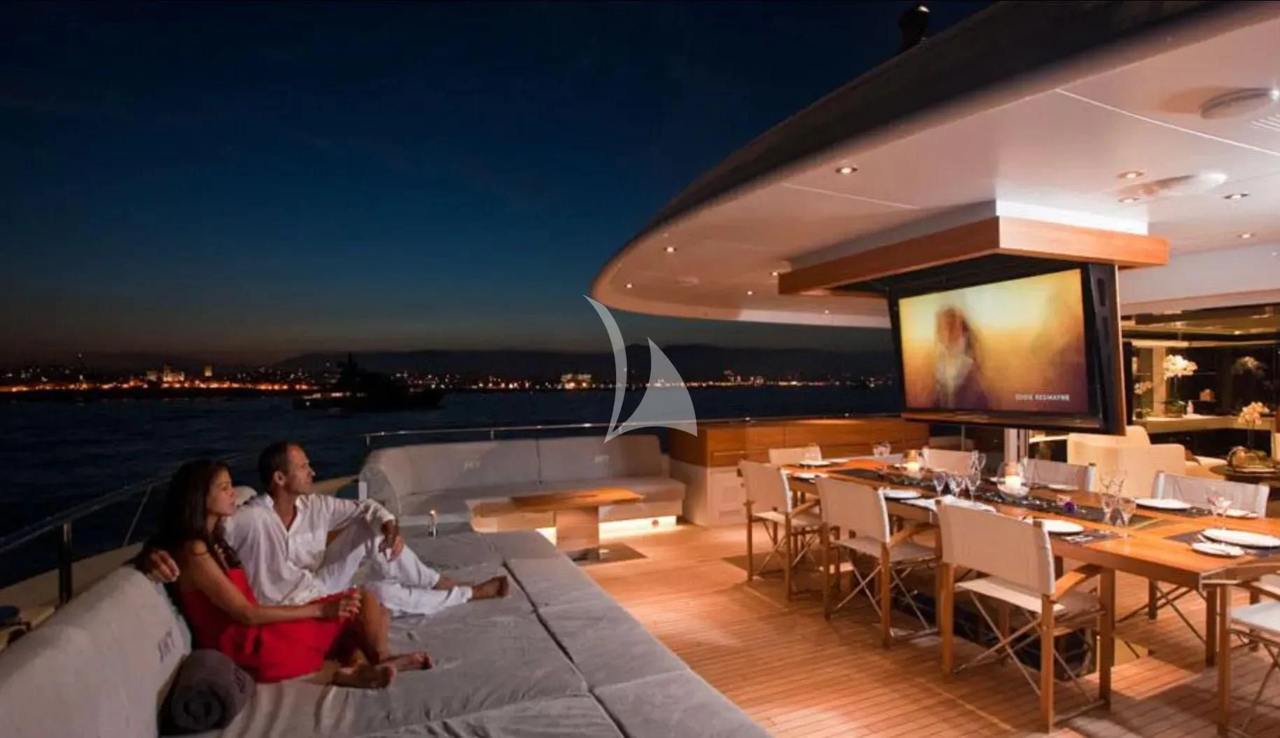 a couple sitting on a couch watching a television aboard TOTEM Yacht for Sale