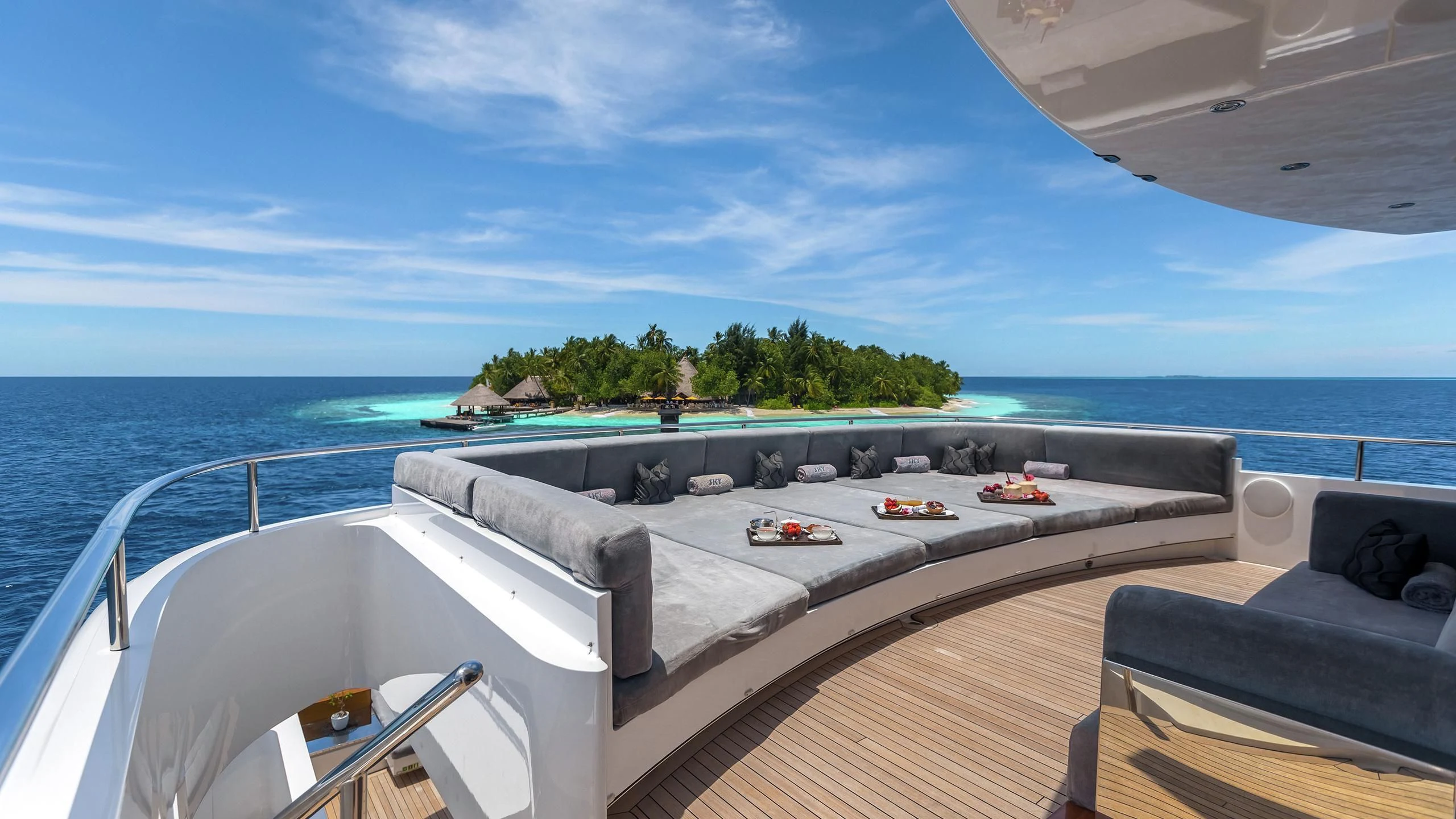 a large pool with a beach and trees in the background aboard TOTEM Yacht for Sale