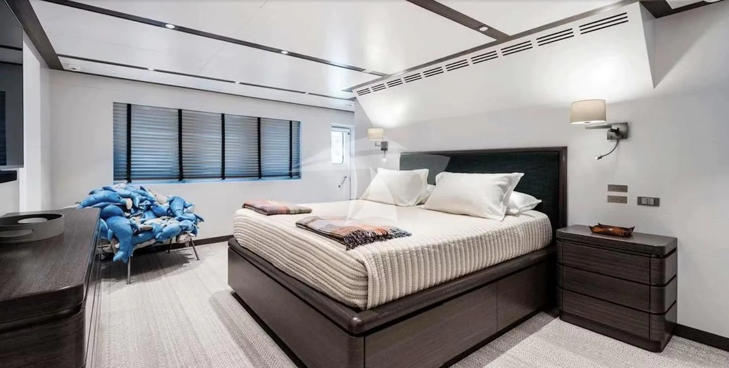 a bedroom with a bed and a blue chair aboard GENESIA Yacht for Sale